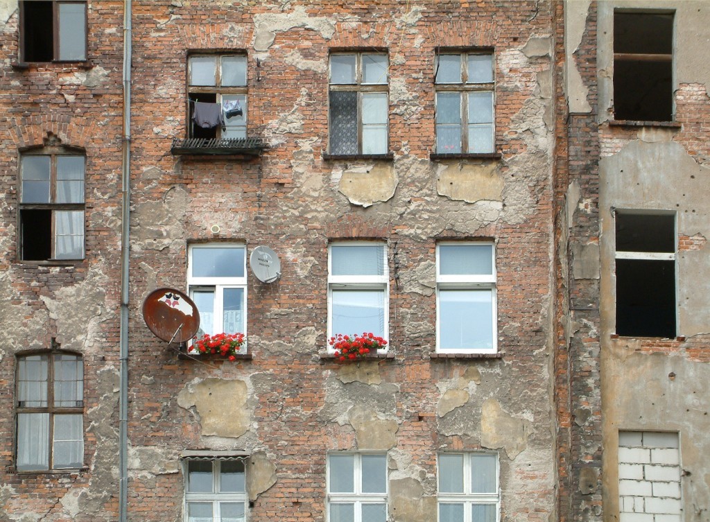 Rote Farbtupfer - Geranien schmücken eine triste, morbide Hausfassade