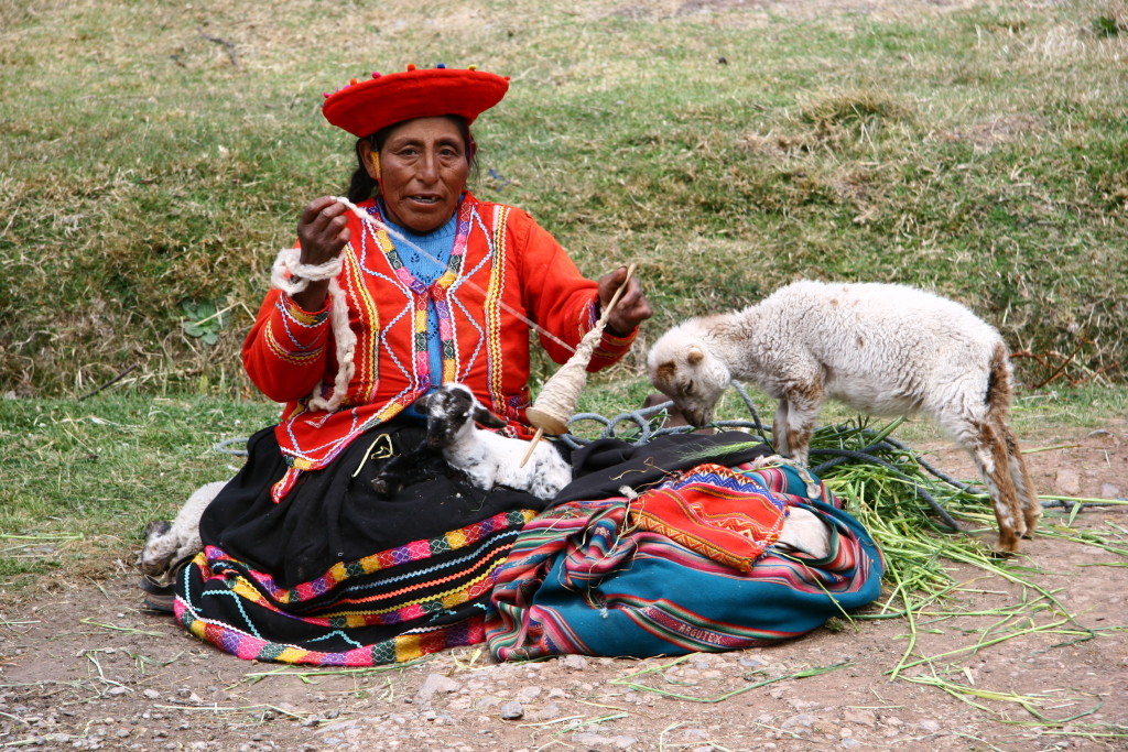 Traditionell gekleidete, peruanische Spinnerin mit Lämmchen