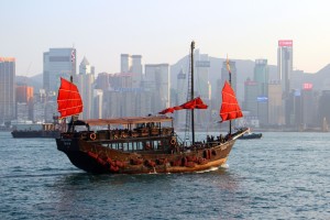 Dschunke mit roten Segeln vor der Skyline von Hongkong