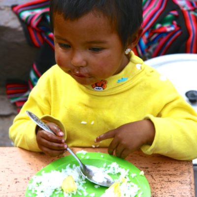 Peruanisches Kind ist Reis mit Gemüse