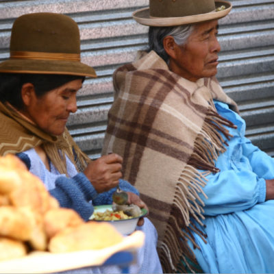 Cholitas auf der Straße beim Mittagessen