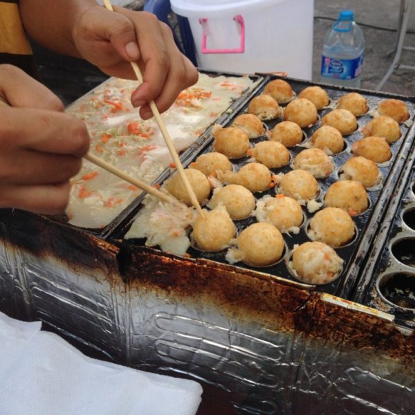Straßenfest in Krabi - Mit Stäbchen und viel Geschick werden kleine Tintenfisch-Teigbällchen vorbereitet.